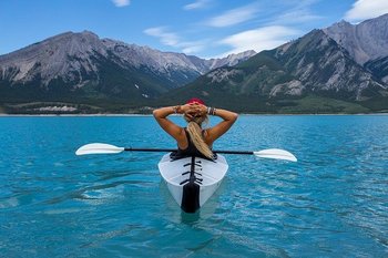 Woman in a kayak looking towards mountains in the distance